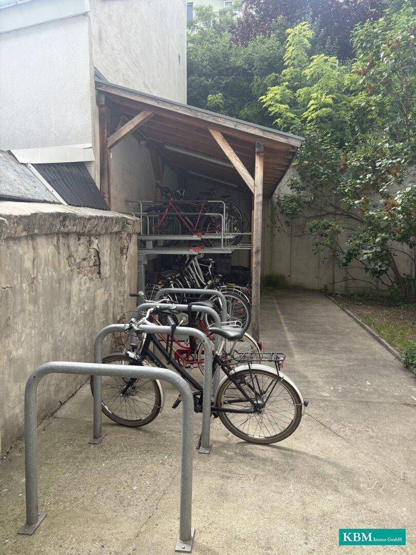 Überdachter Fahrradabstellplatz im Freien mit mehreren Fahrrädern und Ständern.
