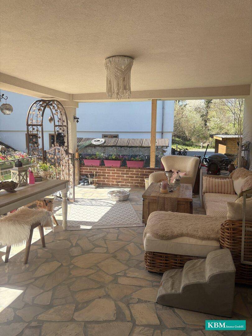 Überdachte Terrasse mit gemütlichen Sitzmöbeln und Blick auf den Gartenbereich.