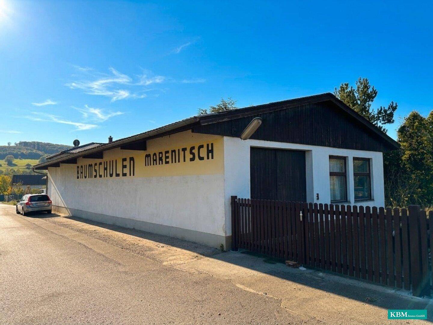 Fassade eines Gebäudes mit der Aufschrift 'BAUMSCHULEN MARENITSCH' und einem Zaun im Vordergrund.