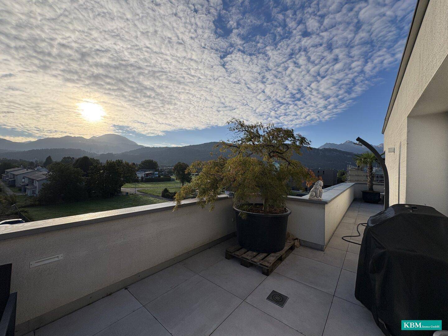 Geräumige Terrasse mit Grill und Topfpflanzen, die eine weite Aussicht auf die umliegende Landschaft bietet.