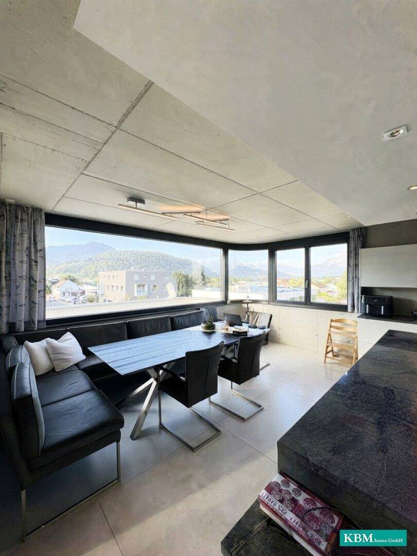 Heller Essbereich mit Eckbank und modernem Tisch, umgeben von großen Fenstern mit Aussicht.