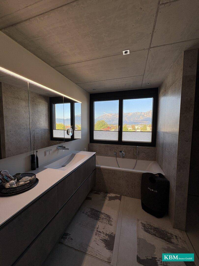 Modernes Badezimmer mit Doppelwaschbecken, Badewanne und Fenster mit Bergblick.
