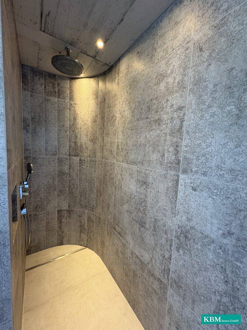 Begehbare Dusche mit modernen Fliesen und Regenduschkopf in einem stilvollen Badezimmer.