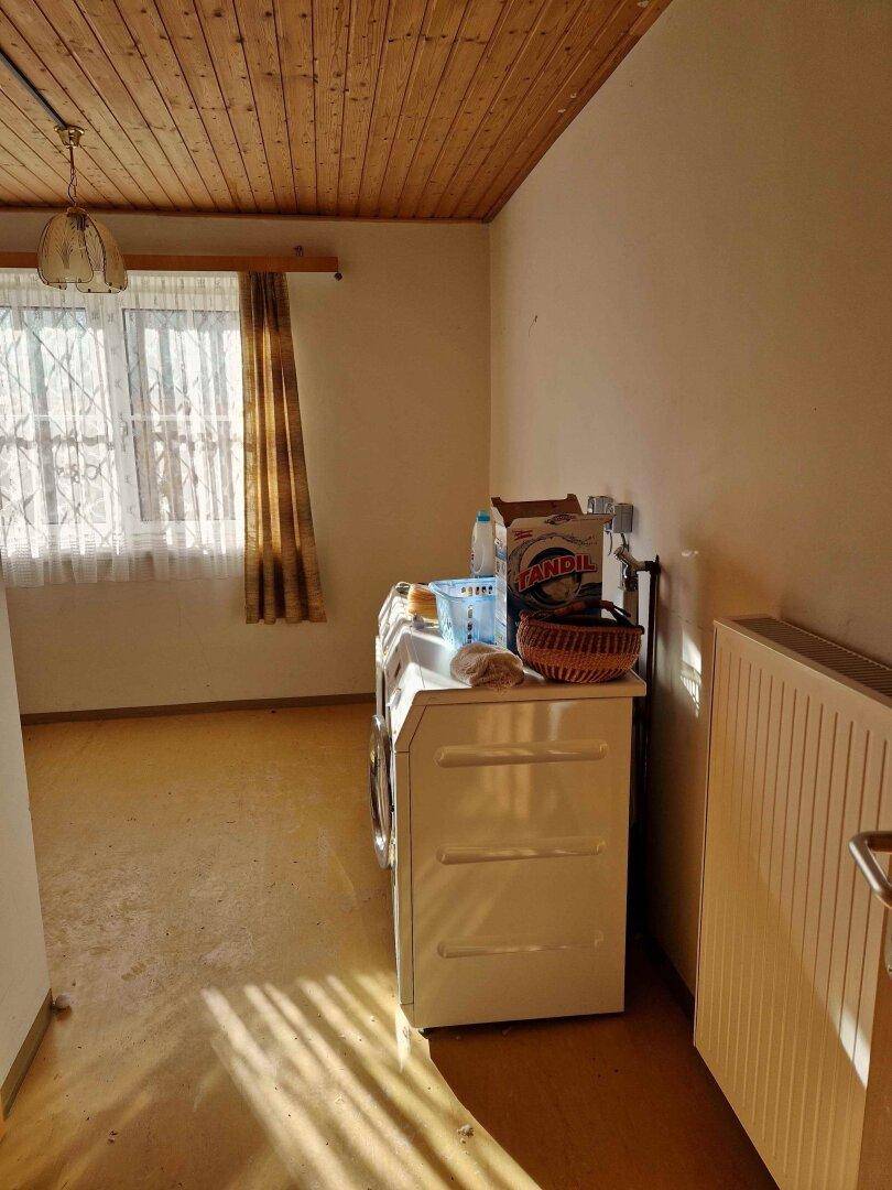 Heller Hauswirtschaftsraum mit Waschmaschine und Fenster für natürliche Belüftung.