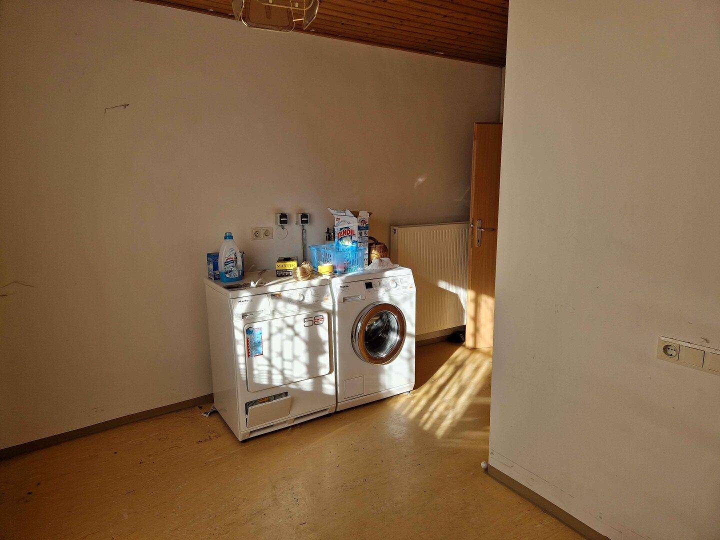 Praktischer Hauswirtschaftsraum mit Waschmaschine, Trockner und Heizkörper.
