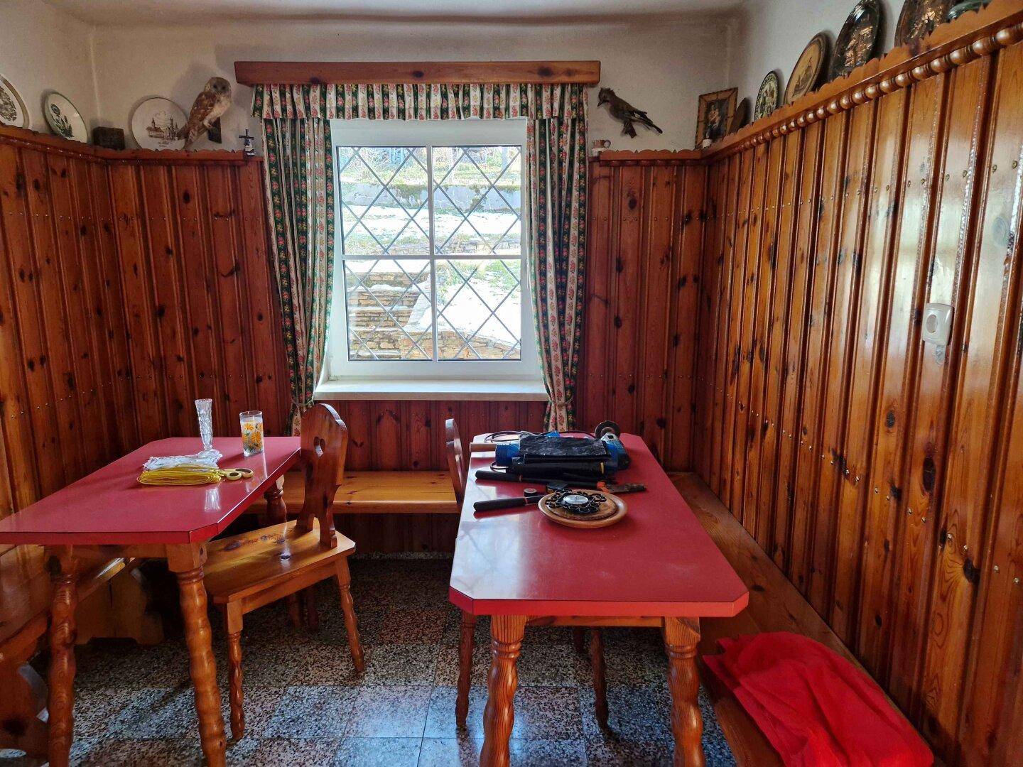 Traditionelle Essecke mit Holzvertäfelung, roten Tischen und Fenster mit Sprossen.