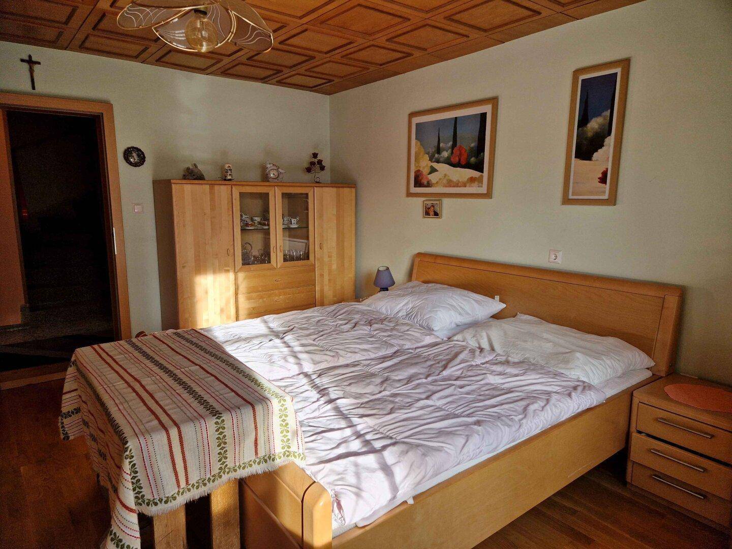 Gemütliches Schlafzimmer mit Doppelbett, Holzdecke und traditionellem Schrank.