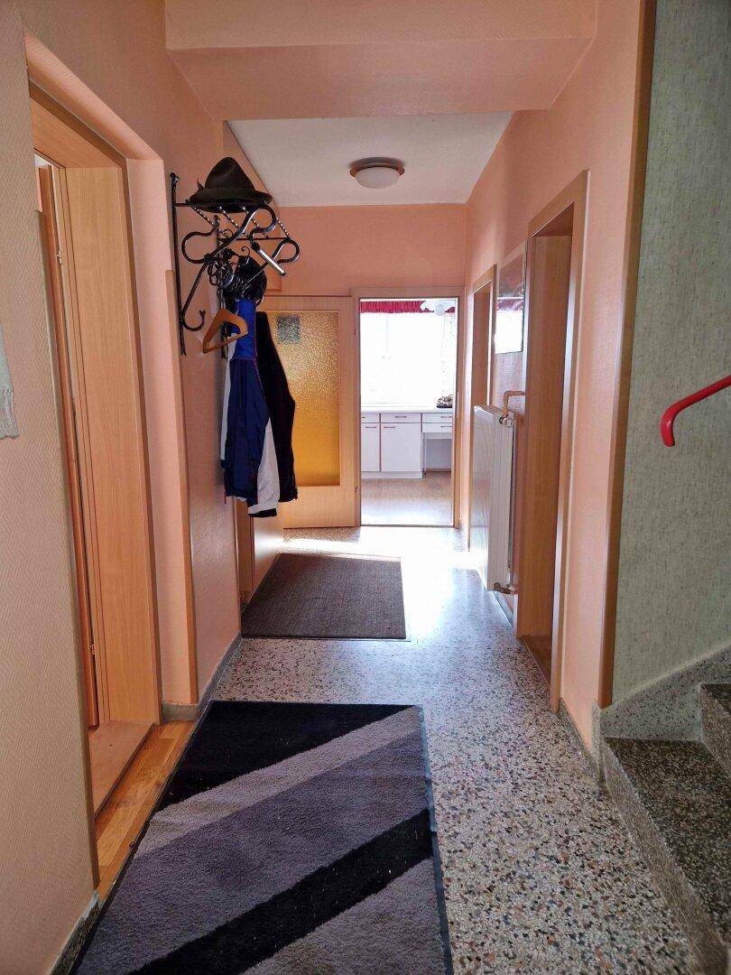 Heller Flur mit Terrazzoboden, Garderobe und Zugang zu weiteren Räumen.
