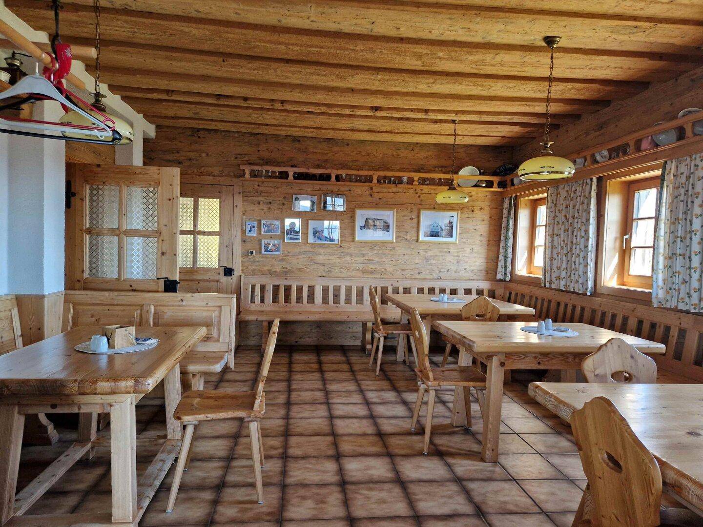 Traditioneller Speisesaal mit viel Holz, gemütlichen Sitzecken und kleinen Fenstern.