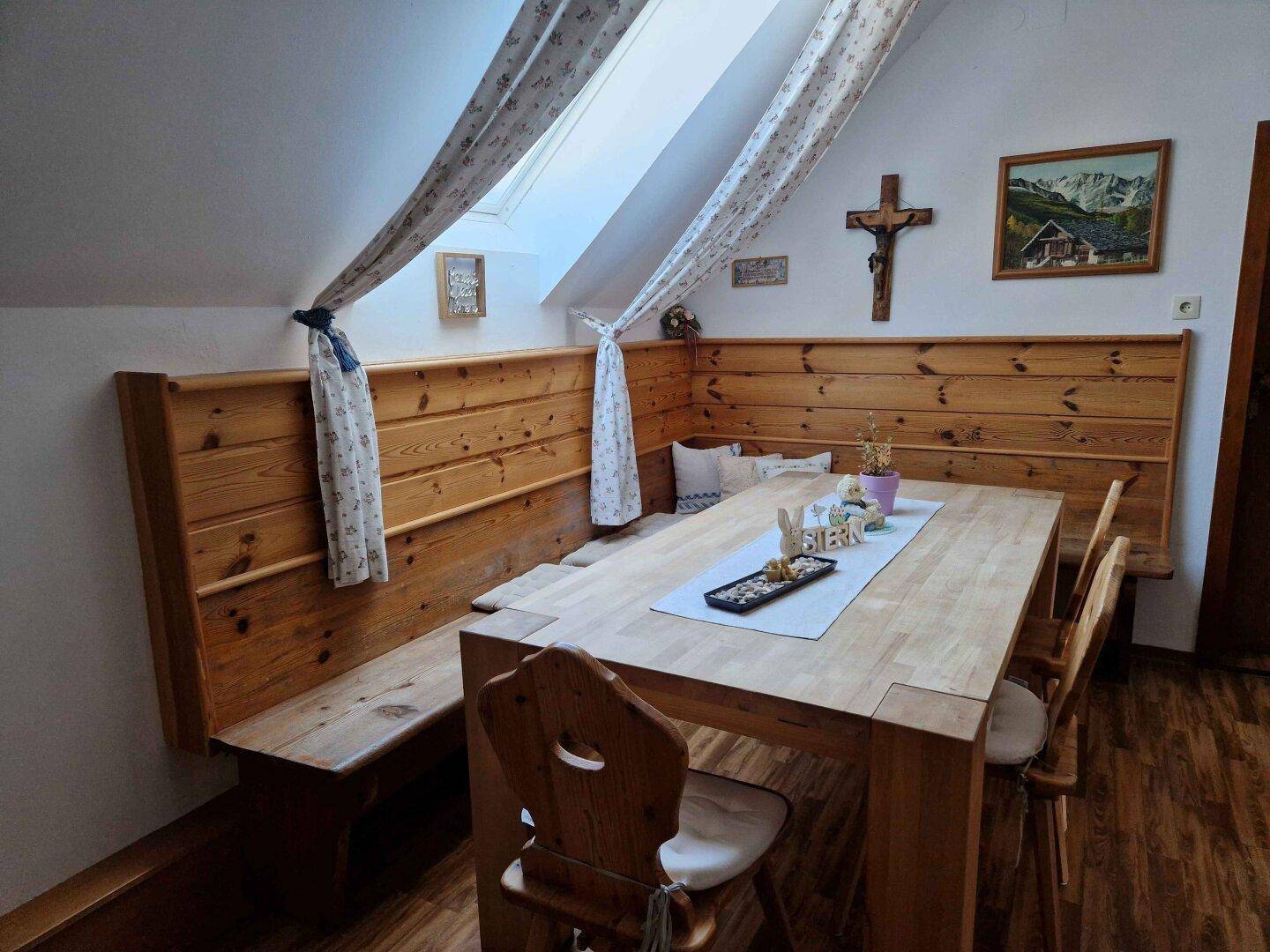 Gemütlicher Essbereich im Dachgeschoss mit Holzbänken, Holztisch und Dachfenster.