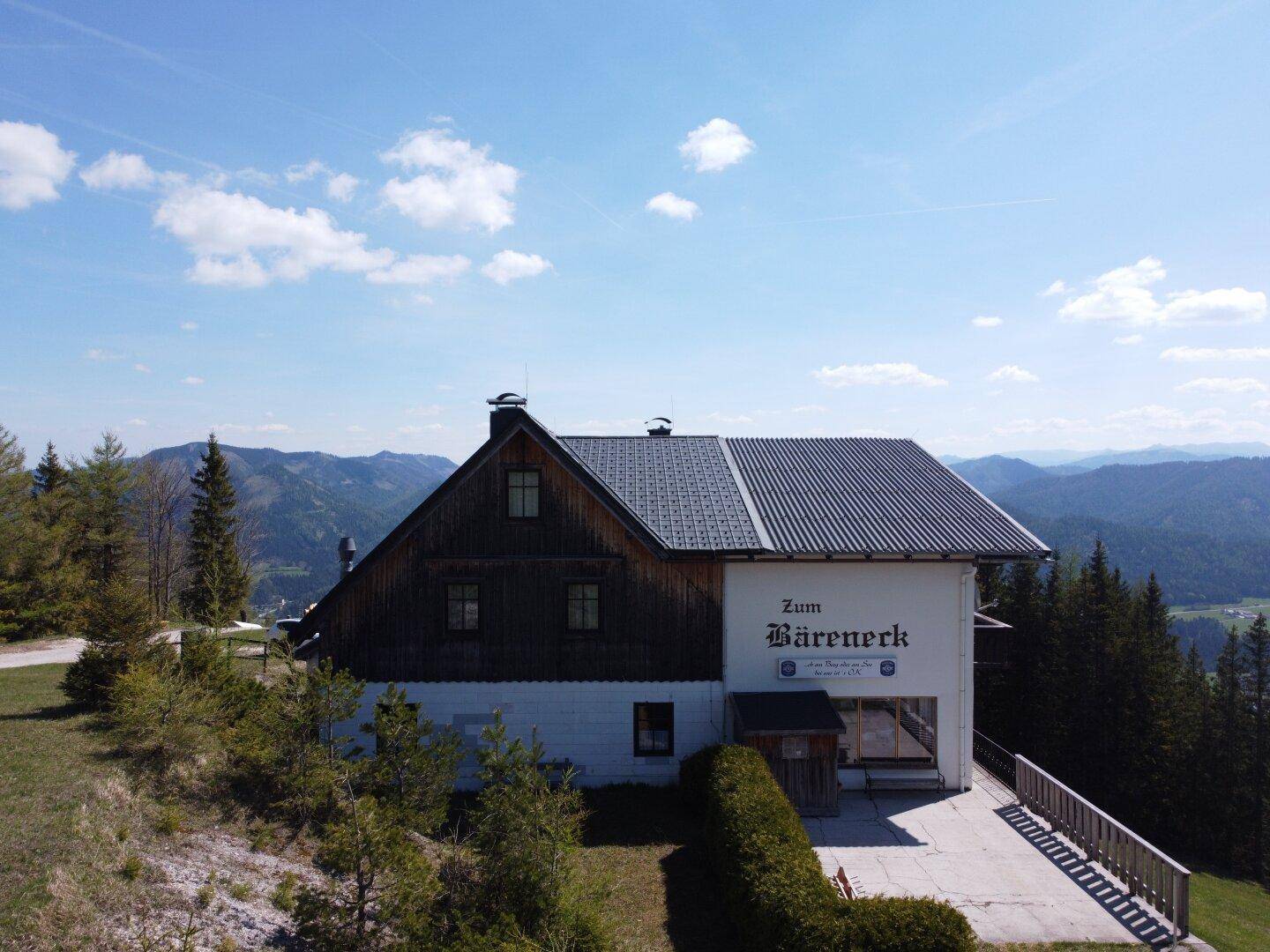 Seitenansicht des Gebäudes im alpinen Stil mit Holzelementen und einem gepflegten Vorplatz.