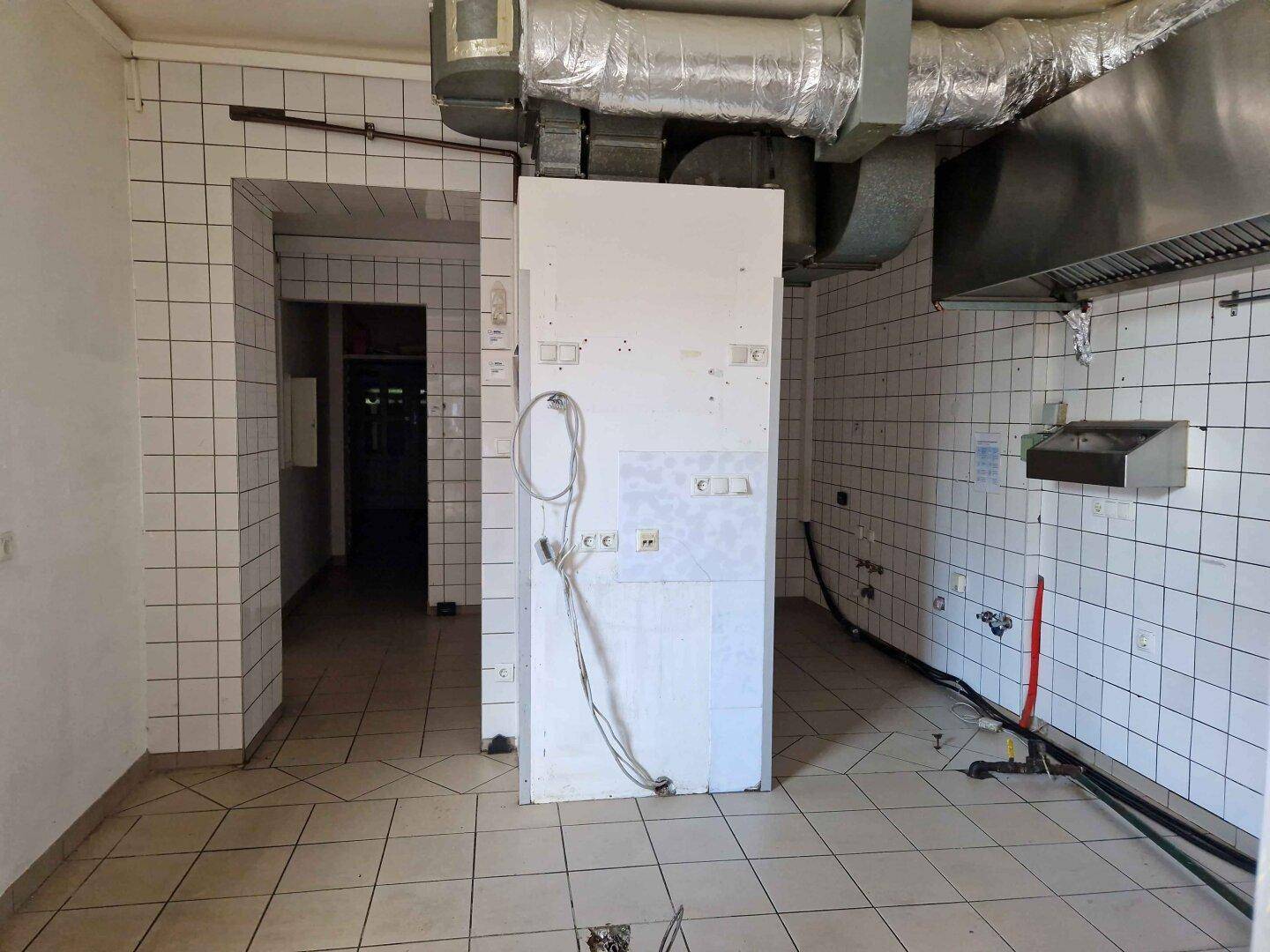 Gefliester Raum mit industrieller Lüftung und Vorbereitung für eine gewerbliche Küche.