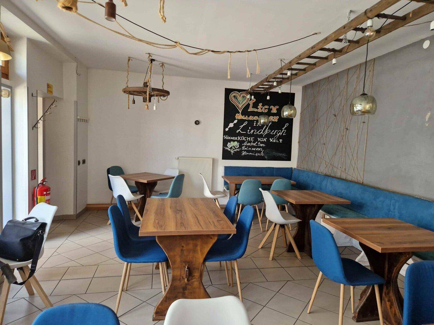 Moderner Essbereich mit blauen Stühlen, Holztischen und einer dekorativen Tafel an der Wand.