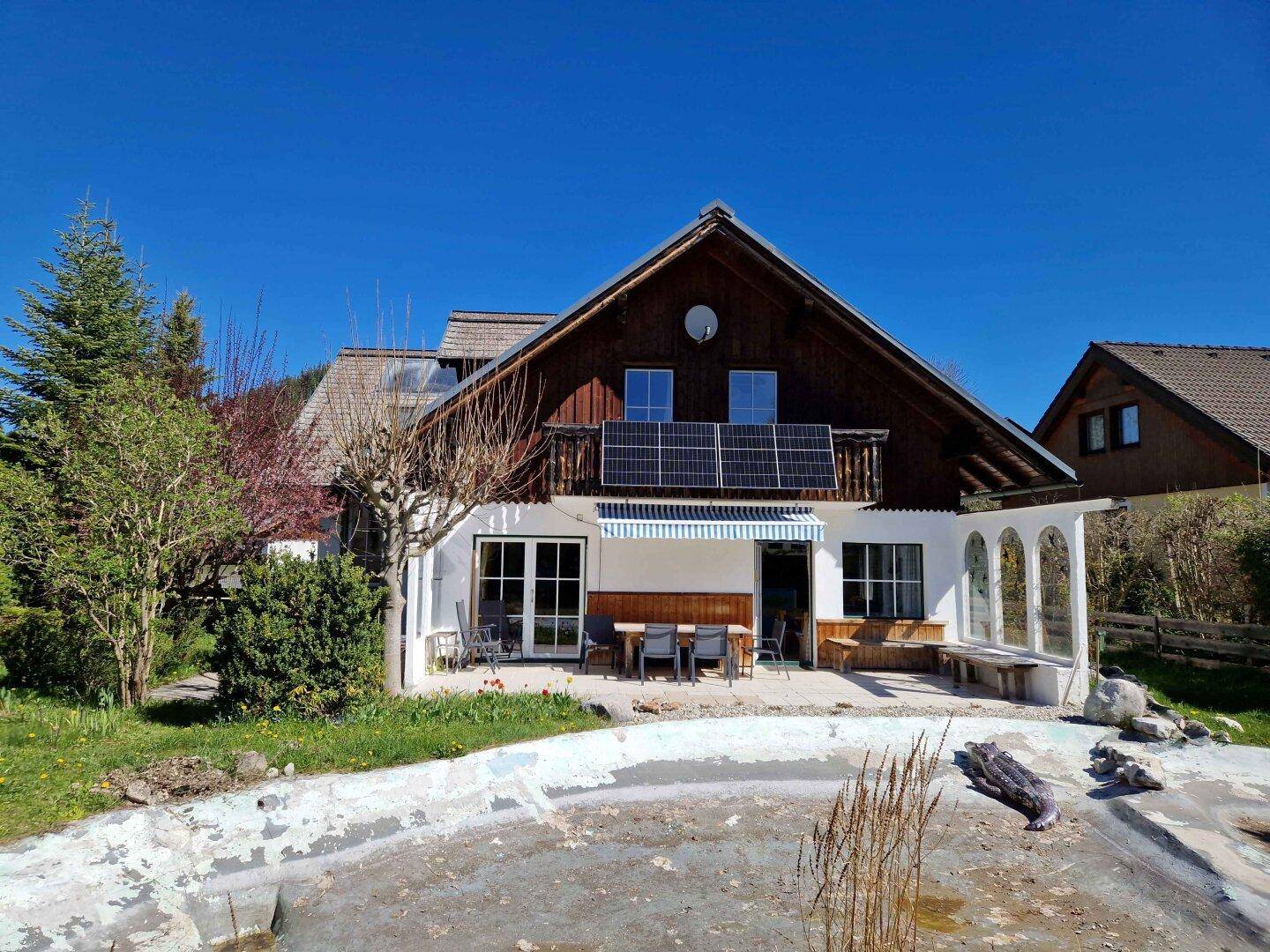 Ansicht des Hauses von hinten mit Terrasse, Garten und einem vorbereiteten Teichbereich.