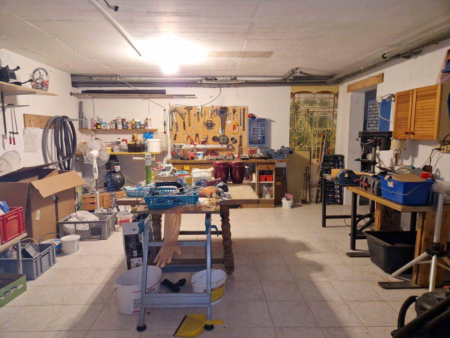 Großer Werkstattraum im Keller mit zahlreichen Werkzeugen, Arbeitsflächen und Stauraum.