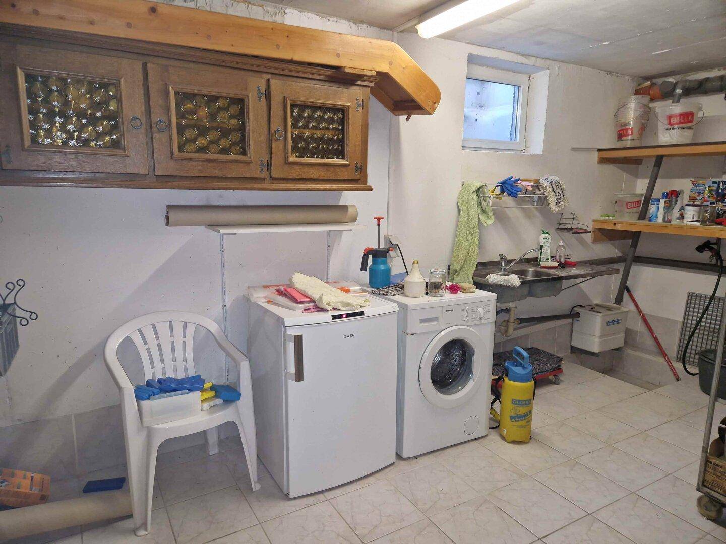 Praktischer Hauswirtschaftsraum im Keller mit Waschmaschine, Trockner und Spülbecken.