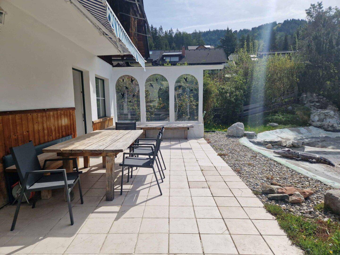 Große gepflasterte Terrasse mit Esstisch und Stühlen, ideal für Mahlzeiten im Freien.