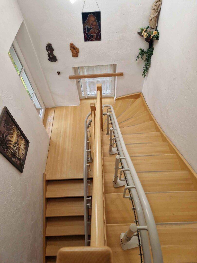 Heller Treppenaufgang mit Holzstufen und Metallgeländer, der die Stockwerke verbindet.