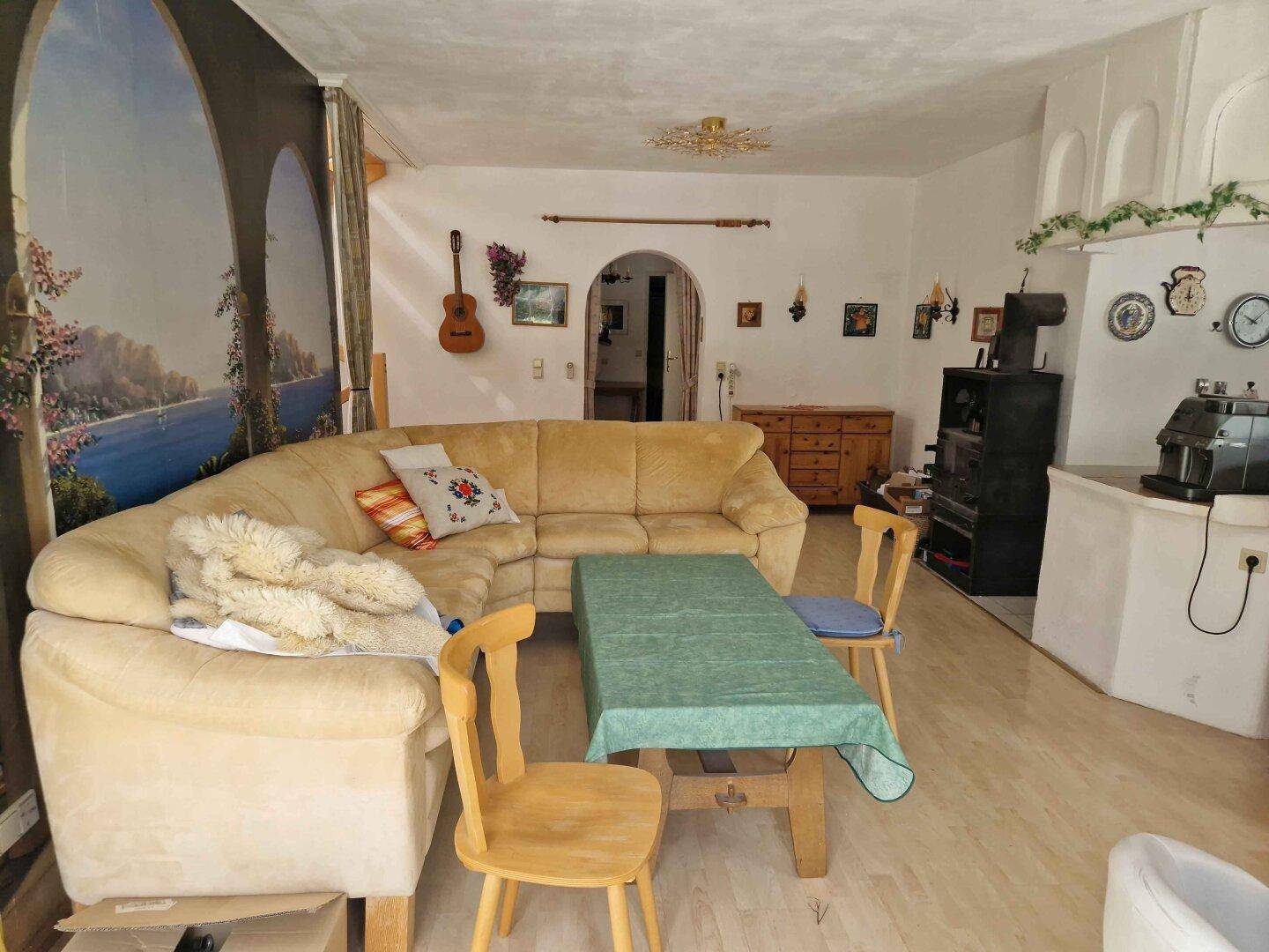 Gemütliches Wohnzimmer mit Ecksofa, Holztisch und traditionellem Kachelofen in rustikalem Stil.
