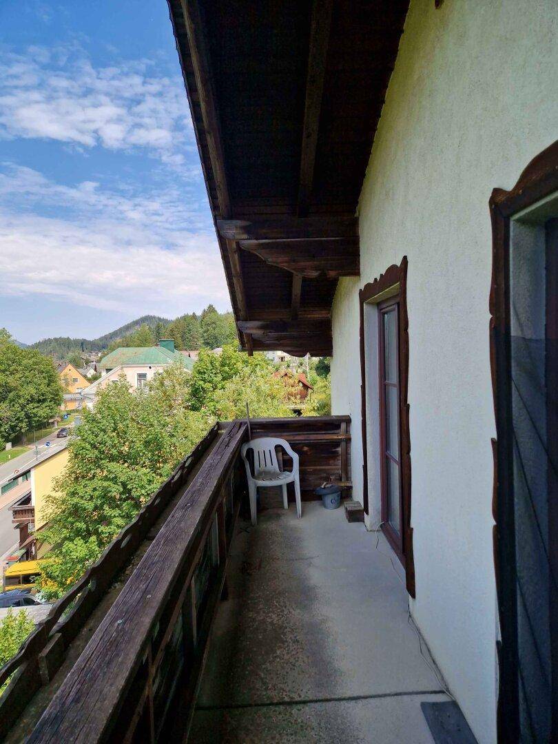 Geräumiger Balkon mit Holzgeländer und malerischem Blick auf das Dorf und die umliegenden Berge.