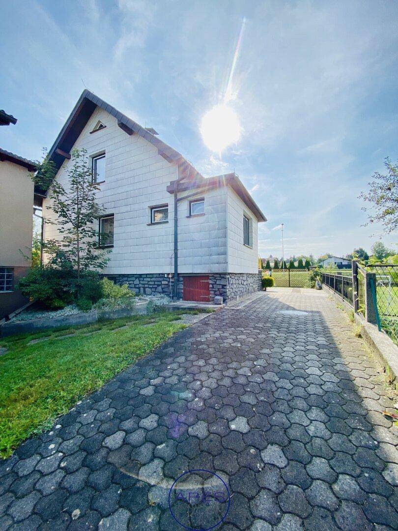 Seitenansicht des Hauses mit gepflasterter Auffahrt und sonnigem Wetter.