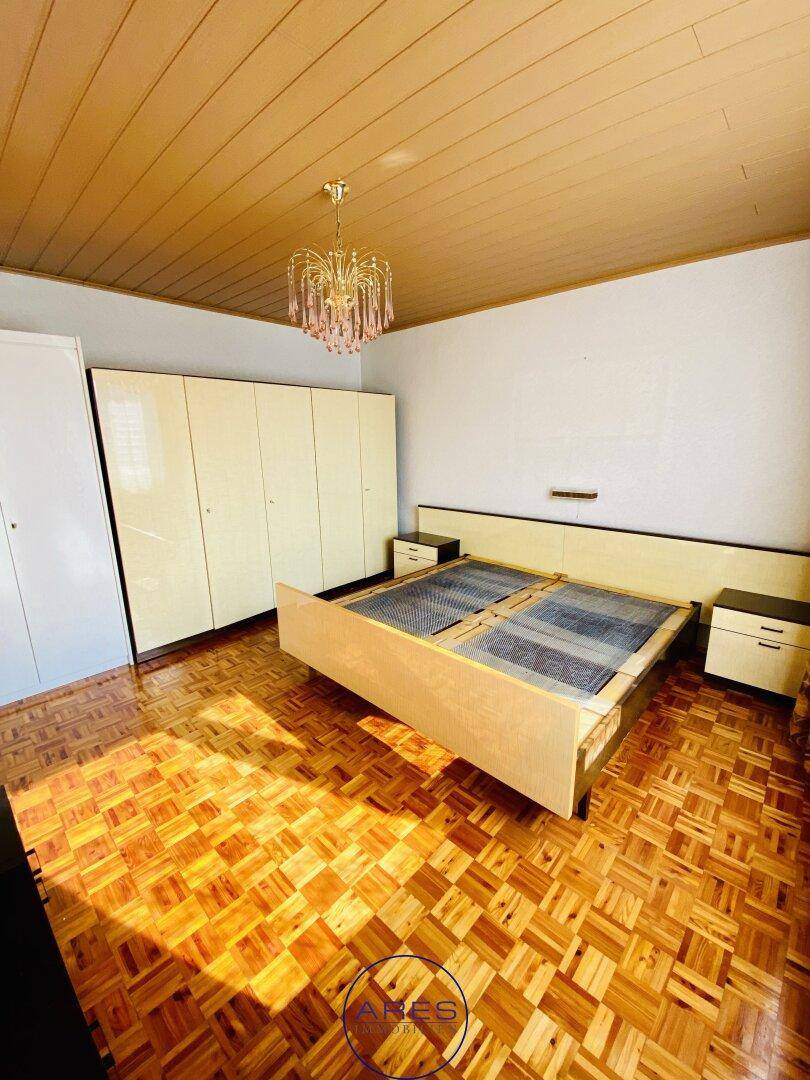 Schlafzimmer mit Parkettboden, Holzdecke und großem Kleiderschrank.