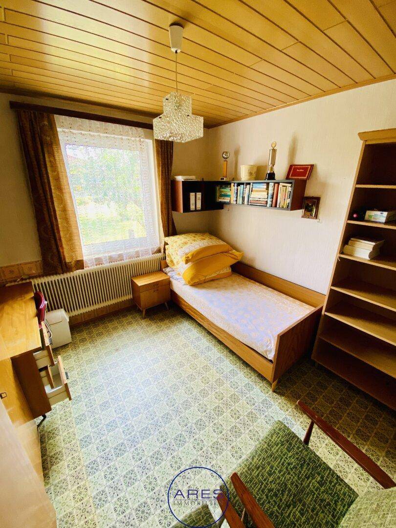 Kleines Schlafzimmer mit Teppichboden, Holzdecke und Einzelbett.