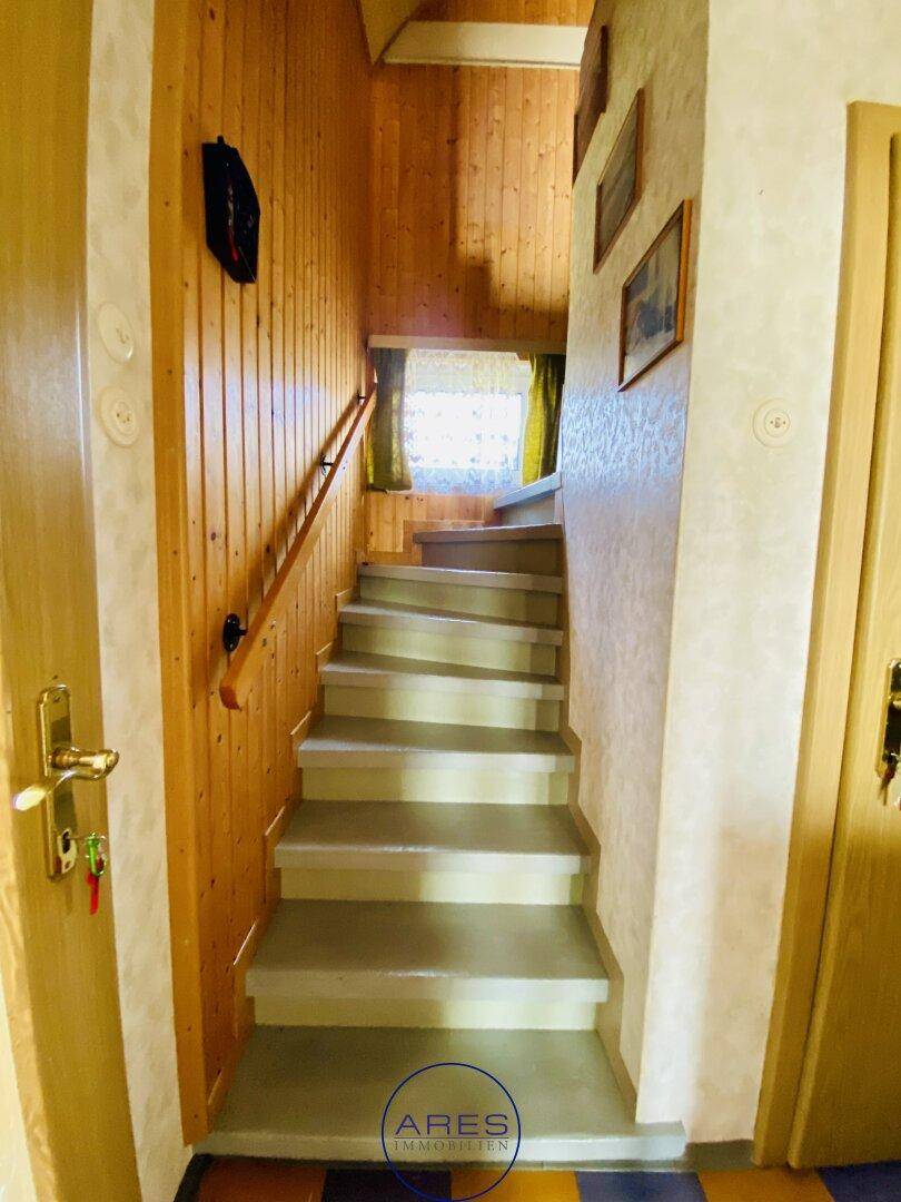 Holzvertäfelte Treppe mit Handlauf, die in die obere Etage führt.