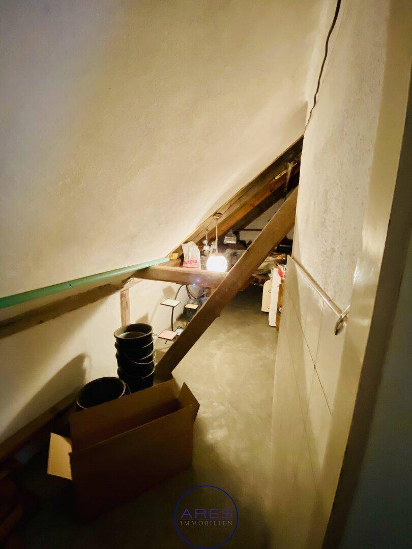 Dachbodenbereich mit schrägen Wänden und sichtbaren Holzbalken, als Abstellraum genutzt.