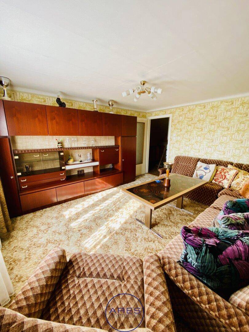 Geräumiges Wohnzimmer mit Teppichboden, großer Wohnwand und gemütlicher Sitzecke.
