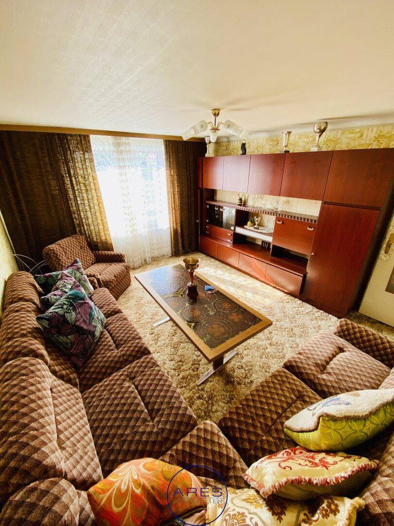 Helles Wohnzimmer mit Teppichboden, großer Wohnwand und Blick nach draußen.