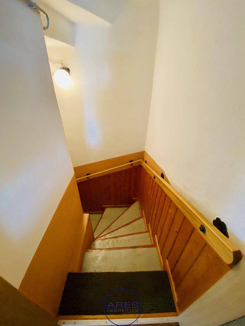 Treppenhaus mit Holzvertäfelung und weiß gestrichenen Wänden.