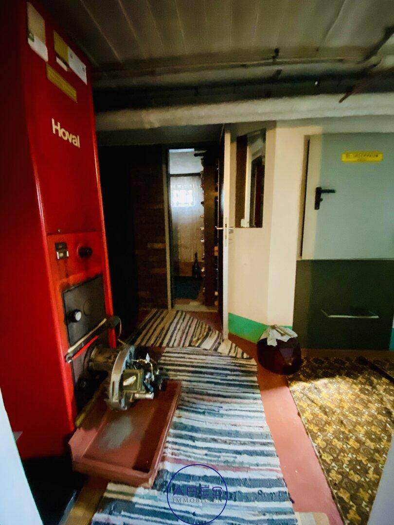 Heizungsraum im Keller mit großem roten Hoval-Heizkessel und sichtbaren Versorgungsleitungen.
