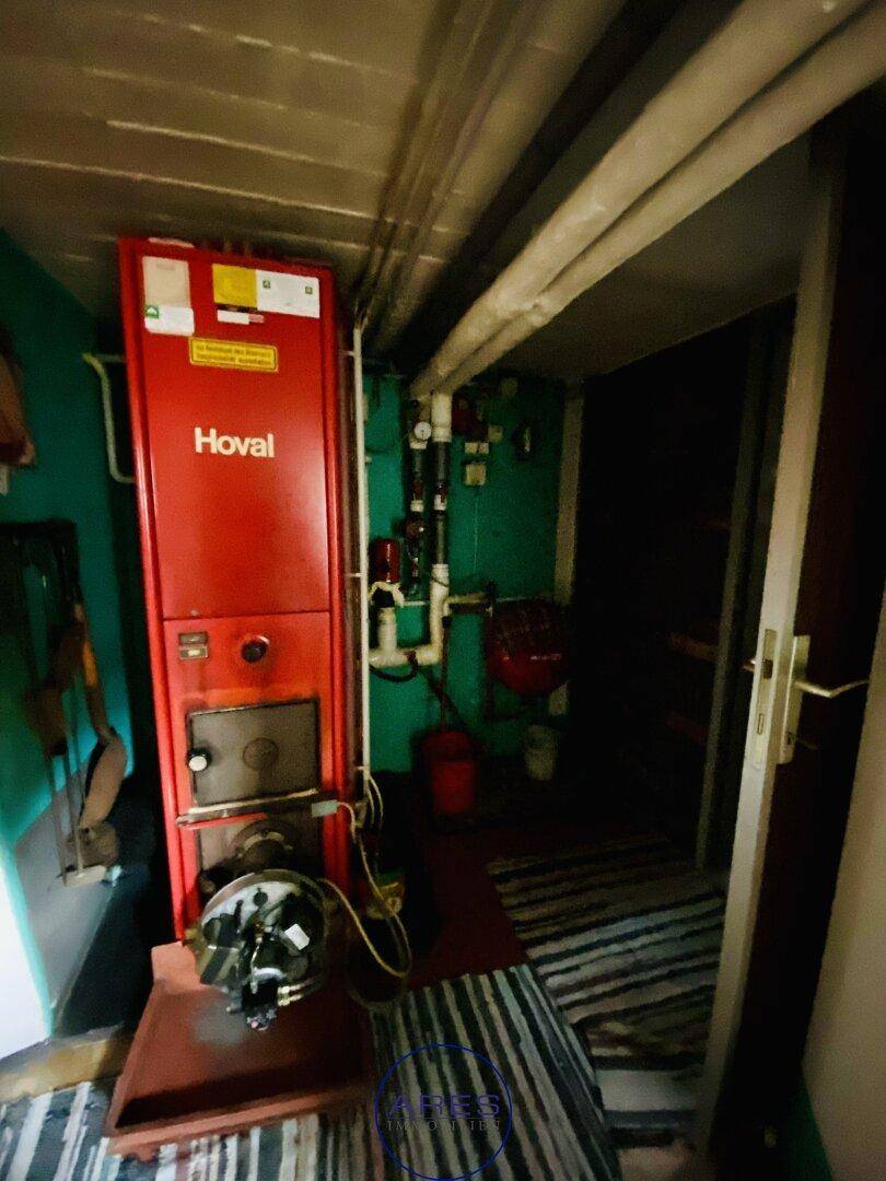 Detailansicht des roten Hoval-Heizkessels im Kellerraum mit angeschlossenen Leitungen.