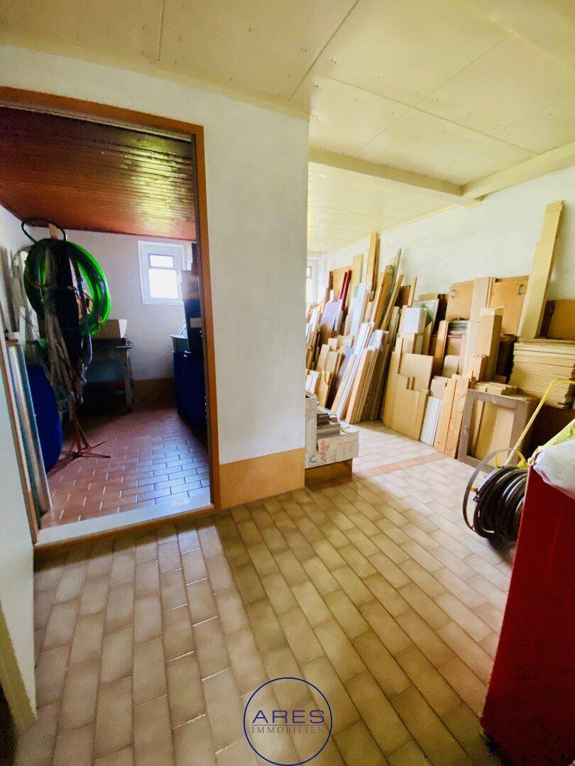 Abstellraum mit gefliestem Boden und gestapelten Holzbrettern, ideal für Lagerzwecke.