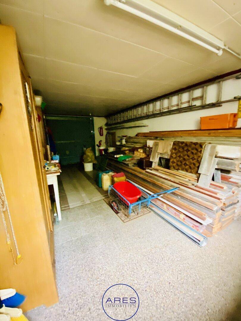 Geräumige Garage oder Lagerfläche mit Betonboden und verschiedenen Werkzeugen und Materialien.