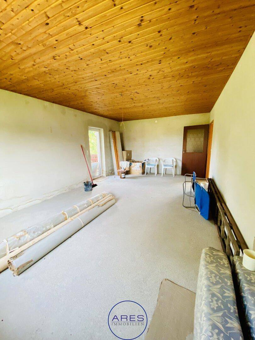 Großer, leerer Raum mit Holzdecke und mehreren Türen, wartet auf Fertigstellung und neue Nutzung.