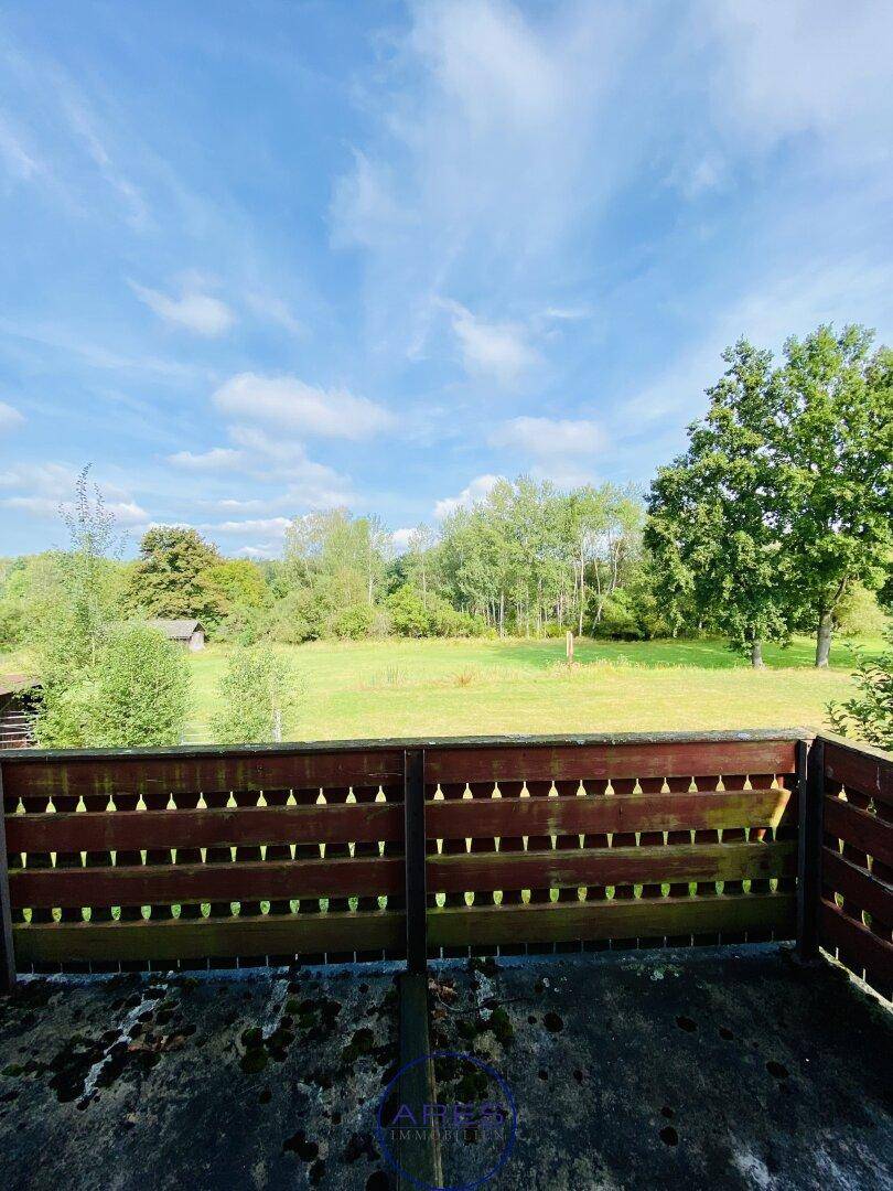 Balkon mit Holzbalkon und weitem Blick über die grüne Landschaft.