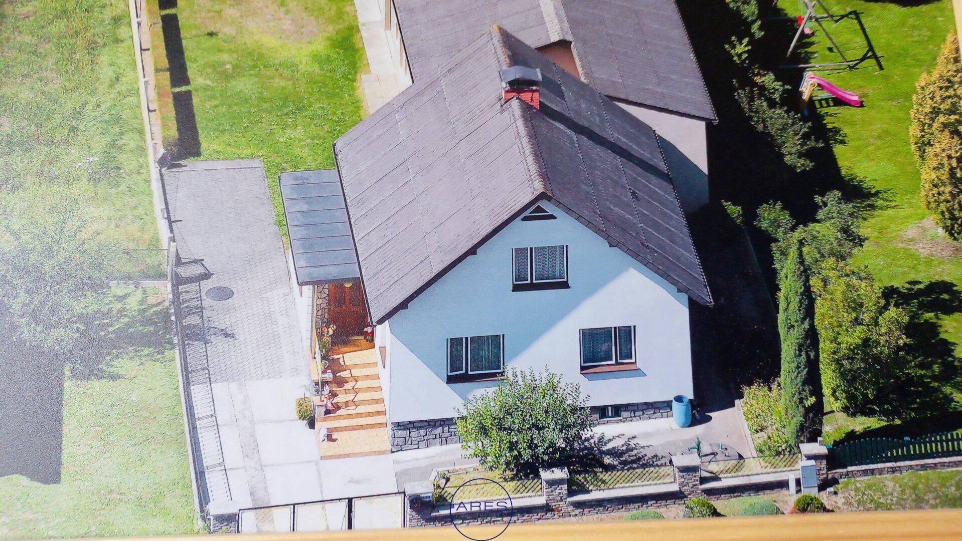Luftaufnahme eines Einfamilienhauses mit Garten, Zufahrt und Satteldach in ländlicher Umgebung.