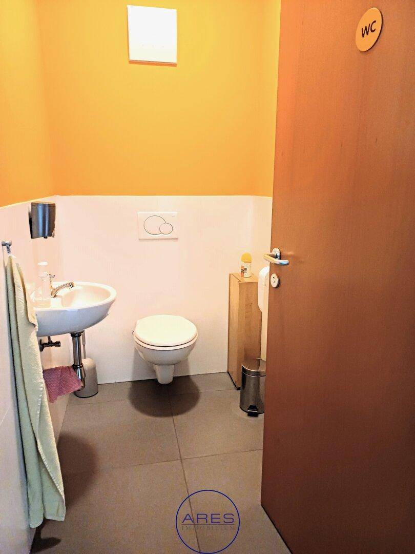 Modernes Gäste-WC mit wandhängender Toilette, kleinem Waschbecken und gelber Wandfarbe.
