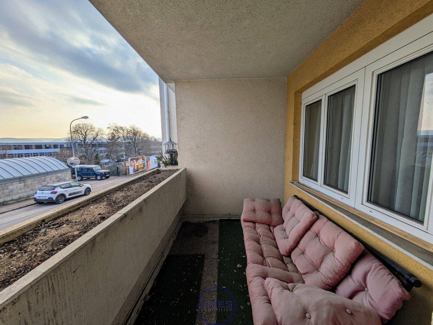 Balkon mit Sitzgelegenheit und Blick auf die Straße, ideal für entspannte Stunden im Freien.