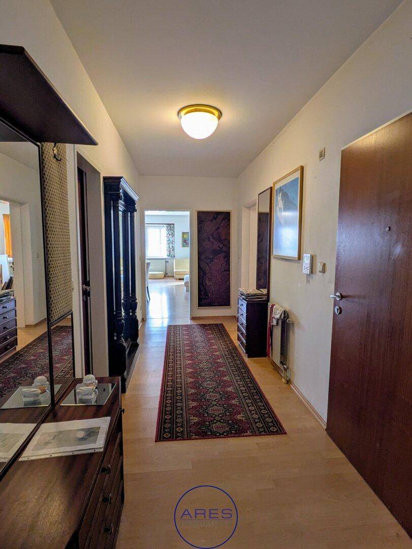 Langer Flur mit Teppichläufer, Spiegeln und traditionellen Möbeln, die zum Wohnbereich führen.
