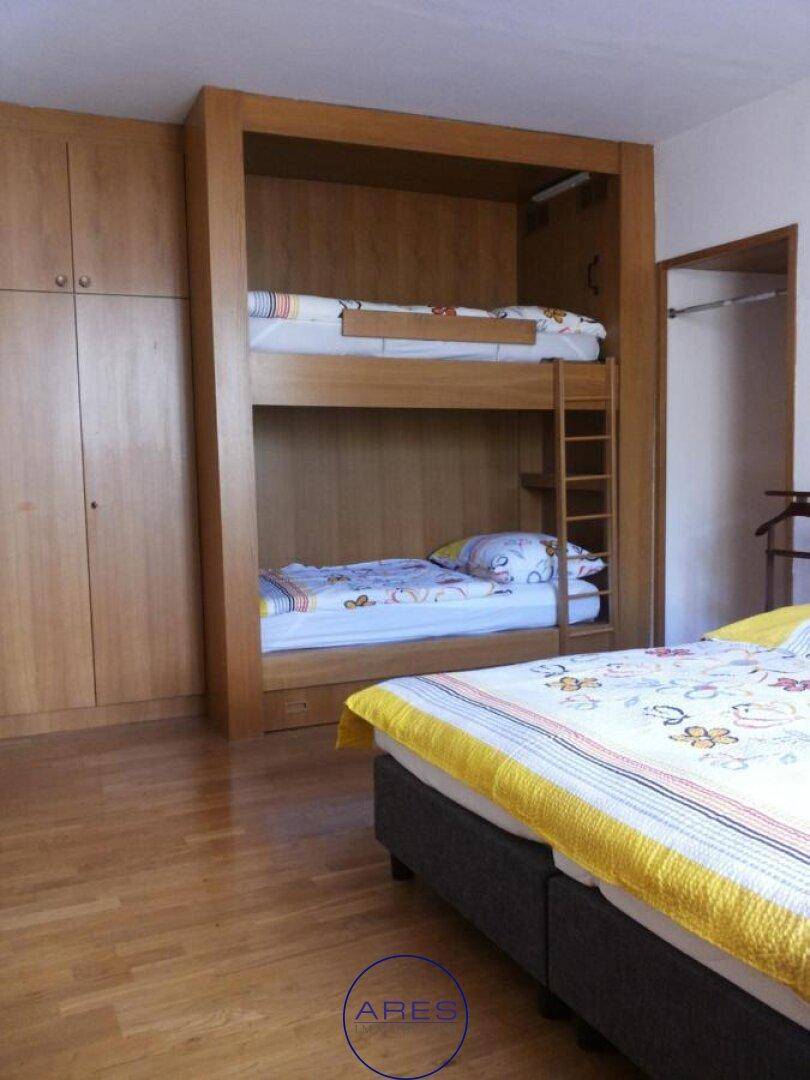 Schlafzimmer mit Etagenbett, Holzschränken und hellem Parkettboden, ideal für Kinder oder Gäste.