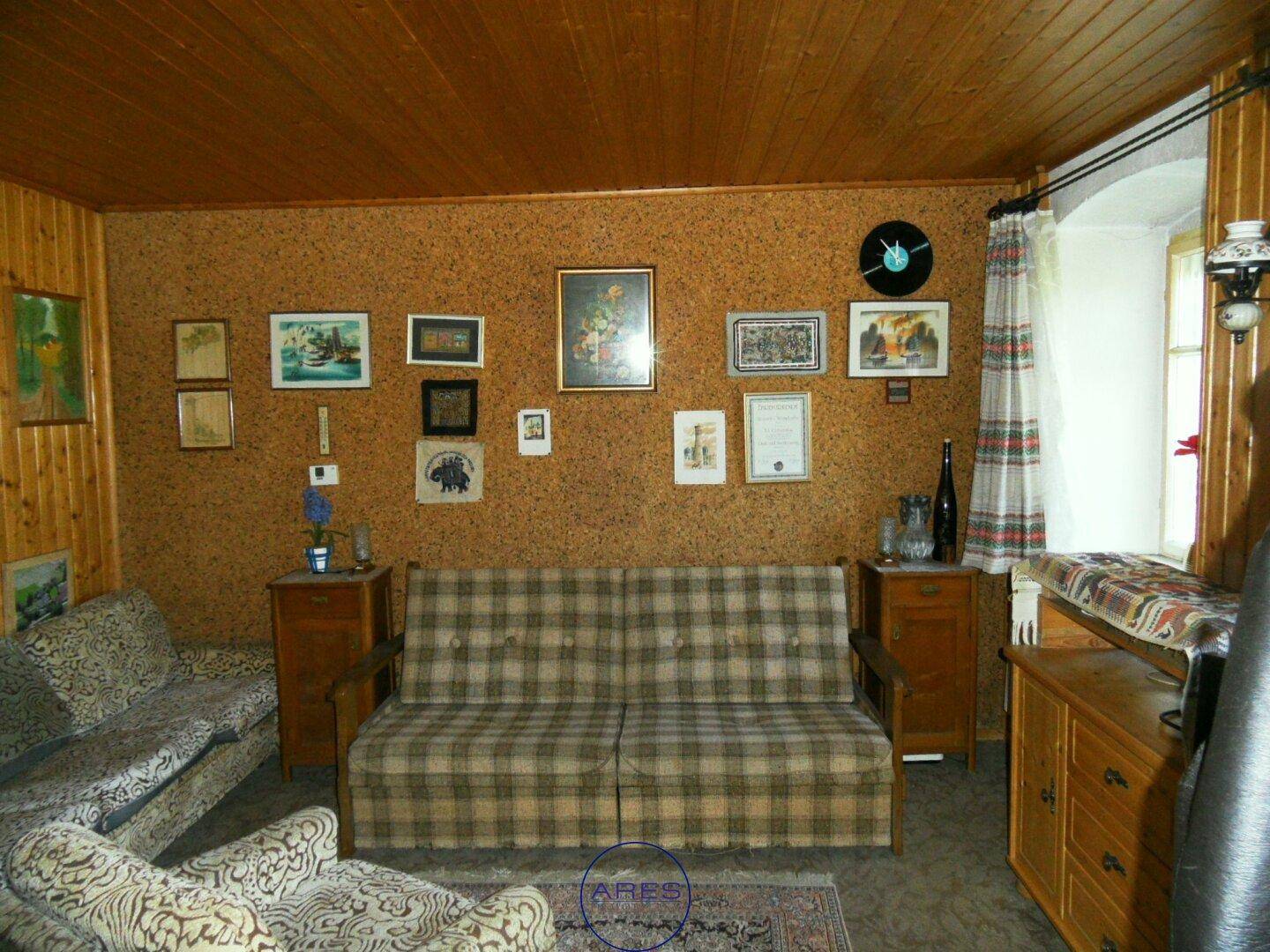 Gemütliches Wohnzimmer mit Holzdecke, Korkwänden und kariertem Sofa in traditionellem Stil.