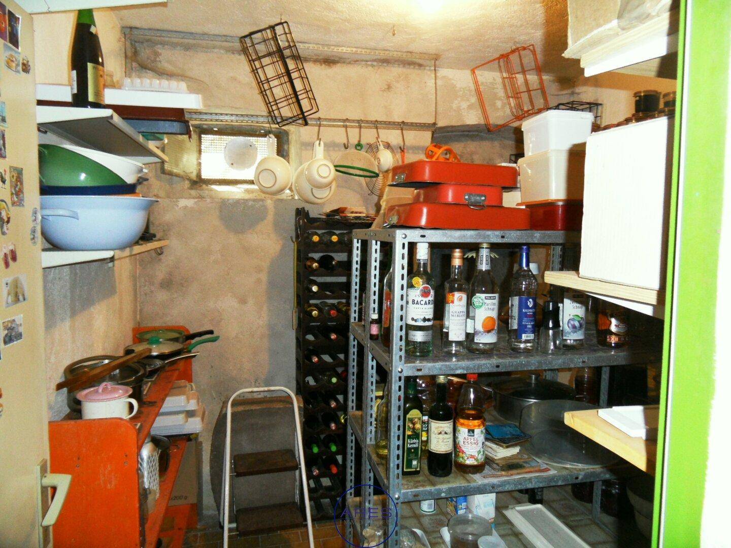 Kleiner Weinkeller mit Metallregalen und verschiedenen Flaschen, ideal zur Lagerung.