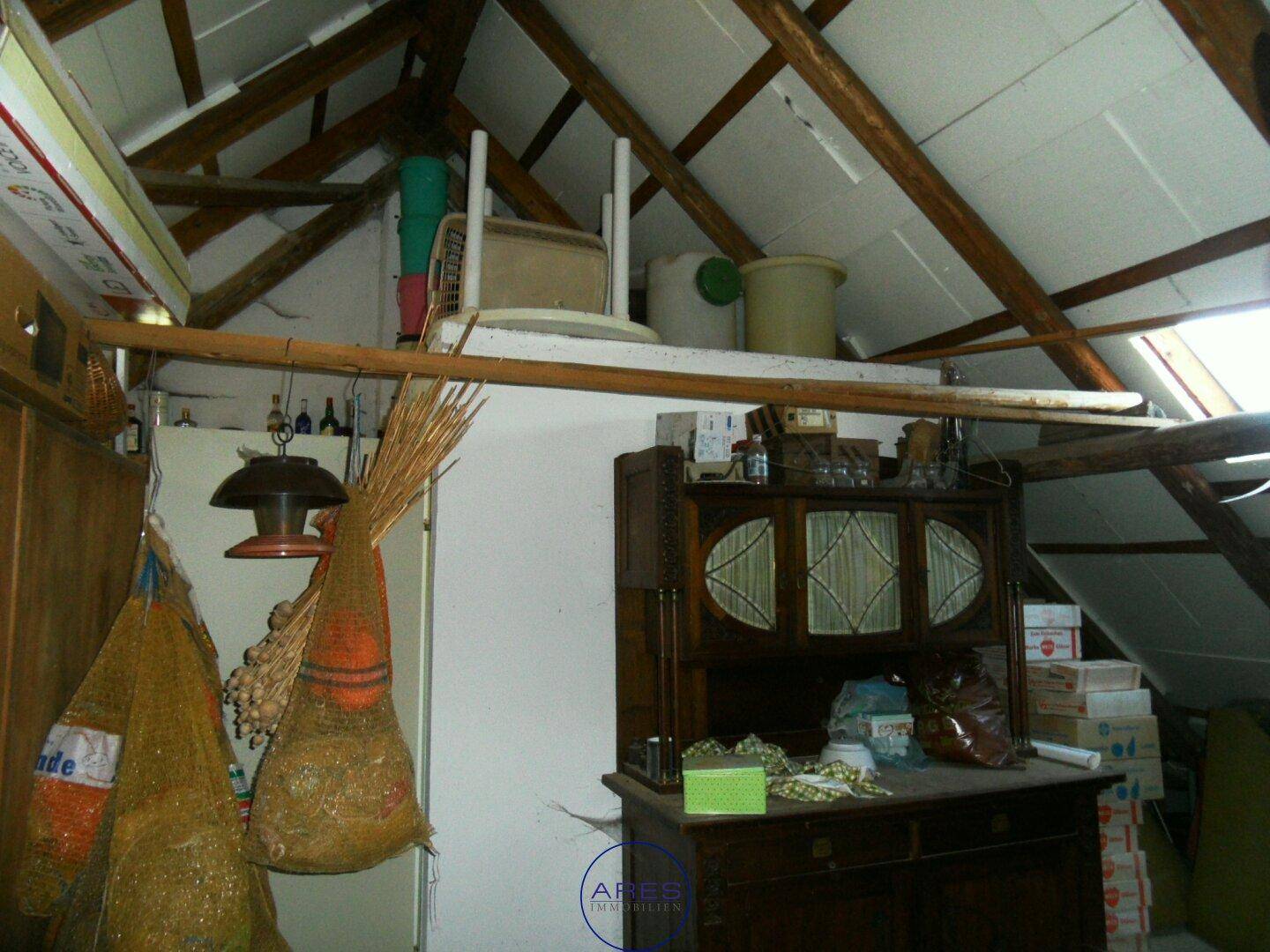 Dachboden als Lagerraum mit sichtbaren Holzbalken und verschiedenen Gegenständen.