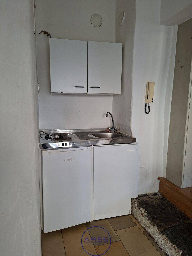 Kleine Küchenzeile mit Spüle, Kochfeld und Kühlschrank, ideal für kompakte Wohnlösungen.