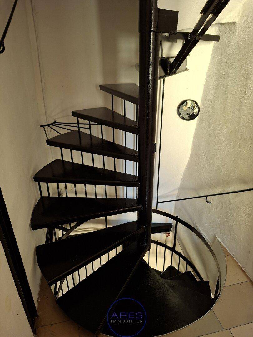 Elegante schwarze Wendeltreppe aus Metall, die verschiedene Etagen miteinander verbindet.