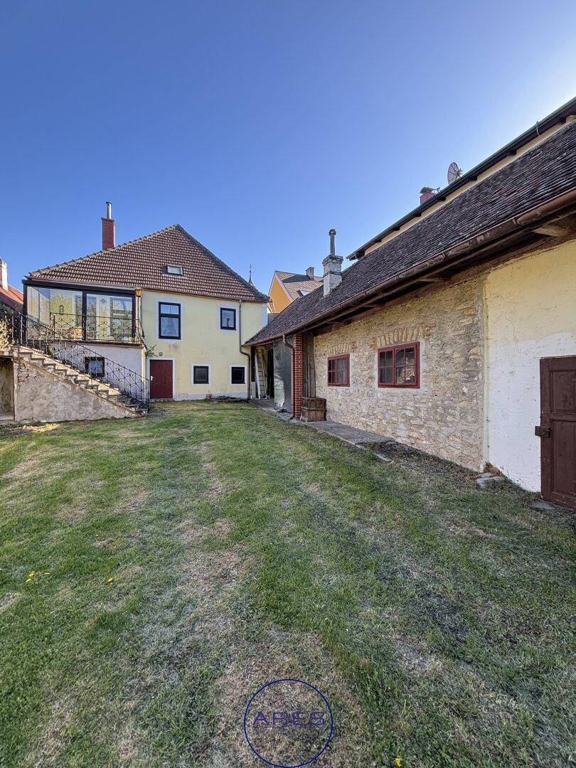 Blick über den Garten auf die Rückseite des Hauses und ein angrenzendes Nebengebäude.
