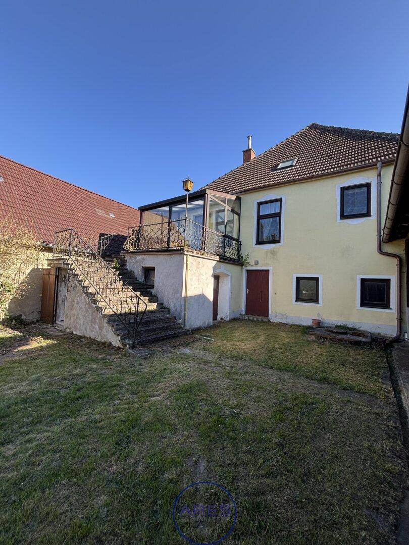 Rückseite des Hauses mit Außentreppe zum Wintergarten und weitläufigem Gartenbereich.